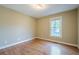 A bright bedroom has hardwood floors and a window offering a view of the outdoors at 6365 Mountain View Trl, Cumming, GA 30041