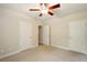 Carpeted bedroom with multiple doors, a ceiling fan, and neutral walls, providing a comfortable and versatile space at 8056 Revere Dr, Mcdonough, GA 30252