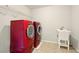 Laundry room with tile floor, red washer and dryer, utility sink, and shelving at 8056 Revere Dr, Mcdonough, GA 30252