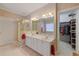 Bathroom featuring double sinks, white cabinets, and a doorway leading to a walk-in closet at 8424 Fairway Dr, Covington, GA 30014