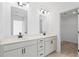 Stylish bathroom featuring double sinks, white cabinets, a large mirror, and an open view into the closet at 3186 Eastham Run Dr, Dacula, GA 30019