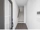 View of the entryway with gray-stained wood floors leading to white stairs and a partially obscured front door at 3186 Eastham Run Dr, Dacula, GA 30019