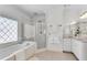 Elegant bathroom with a soaking tub, glass-enclosed shower, and decorative diamond-patterned window at 8111 Lawnview Dr, Alpharetta, GA 30022