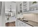 Bright butler's pantry with granite countertops, white cabinets, and glass shelving, perfect for storage and serving at 8111 Lawnview Dr, Alpharetta, GA 30022