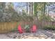 Cozy backyard featuring a stone patio with red Adirondack chairs and lush greenery at 3261 Turtle Lake Se Ct, Marietta, GA 30067