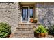 Charming front entrance features stone accents, a black door, and decorative potted plants at 3261 Turtle Lake Se Ct, Marietta, GA 30067