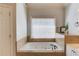 Bright bathroom featuring a soaking tub with jets, and natural stone surround at 1175 Lamont Cir, Dacula, GA 30019