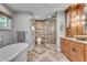 Luxurious bathroom featuring freestanding tub, glass enclosed shower, wooden cabinets, herringbone tile floors, and ample natural light at 1233 Poplar Grove Ne Dr, Atlanta, GA 30306