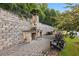 Outdoor fireplace and seating area with stone retaining wall and mature trees at 1829 Hislop Ln, Chamblee, GA 30345