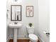 Powder room featuring a pedestal sink, toilet, floral wall art, and hardwood floors at 3314 Ridge Manor Way, Dacula, GA 30019