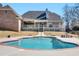 A backyard view of the in-ground swimming pool from the pool deck, surrounded by trees and shrubbery at 8531 N Shore Dr, Jonesboro, GA 30236