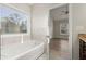 Bright bathroom showcasing soaking tub with tile surround and a view into the bedroom at 411 Spring Lake Hls, White, GA 30184