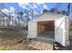 Large outbuilding with open doors, wooden flooring and ramp, surrounded by lush greenery and a fenced yard at 411 Spring Lake Hls, White, GA 30184
