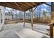 Covered patio area with concrete flooring overlooking the backyard and trees at 411 Spring Lake Hls, White, GA 30184