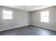 Bright bedroom featuring two windows, gray walls, and sleek gray hardwood floors at 4620 Central Dr, Stone Mountain, GA 30083