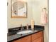Bathroom featuring dark granite countertop, wood cabinets, bronze fixtures, and modern mirror at 5156 Olive Branch Cir, Powder Springs, GA 30127