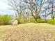View of the large backyard with tall trees surrounding and a storage shed at 2022 Cook Rd, Decatur, GA 30032