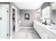 Bright bathroom with double vanity, white cabinets, tile flooring, and a glass-enclosed shower at , Locust Grove, GA 30248