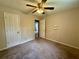Cozy bedroom featuring carpet floors, ceiling fan, and door to hallway at 3989 Woodland Se Cir, Conyers, GA 30013