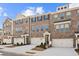 Charming brick townhomes feature attached garages, covered entries, and manicured landscaping under a bright blue sky at 3192 Eastham Run Dr, Dacula, GA 30019