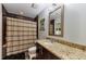 Well-appointed bathroom featuring granite countertops, a decorative mirror, and a shower with dark tile at 1080 Peachtree Ne St # 1208, Atlanta, GA 30309