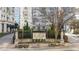 View of the community entrance sign among trees, landscaping, and the building in the background at 195 14Th Ne St # 2105, Atlanta, GA 30309