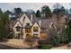 An evening exterior view showcases a stone home with large windows, a pool, covered patio, and meticulous landscaping at 938 Crescent River Pass, Suwanee, GA 30024