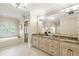 Bright bathroom with tub, double vanity, and a large decorative mirror at 938 Crescent River Pass, Suwanee, GA 30024