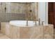 Close up of bathroom soaking tub with bronze fixtures and stone surround at 938 Crescent River Pass, Suwanee, GA 30024