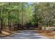 Beautiful, custom wood driveway gate surrounded by dense trees at 938 Crescent River Pass, Suwanee, GA 30024