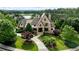 Stunning aerial view of a luxurious stone house with lush greenery, landscaping, and a circular driveway at 938 Crescent River Pass, Suwanee, GA 30024