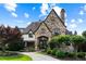 Stone and brick home featuring an arched entryway, manicured landscaping and a circular driveway at 938 Crescent River Pass, Suwanee, GA 30024