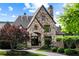 Stone home exterior featuring an arched entryway, manicured landscaping and a circular driveway at 938 Crescent River Pass, Suwanee, GA 30024