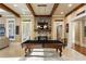 The spacious game room features a stone fireplace, a billiard table, and exposed beams, and views to the outside at 938 Crescent River Pass, Suwanee, GA 30024