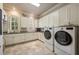 Well-equipped laundry room with white cabinets, modern washer and dryer, and tiled flooring at 938 Crescent River Pass, Suwanee, GA 30024