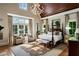 Serene main bedroom featuring a four-poster bed, ample natural light, and a relaxing sitting area at 938 Crescent River Pass, Suwanee, GA 30024