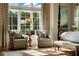 Sunlit main bedroom with a sitting area, beautiful rug, and views of the lush outdoor landscape at 938 Crescent River Pass, Suwanee, GA 30024