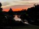 Picturesque pond view at sunset bordered by mature trees on the property at 938 Crescent River Pass, Suwanee, GA 30024