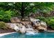 Rock waterfall flows into the pool creating a tranquil backyard retreat at 938 Crescent River Pass, Suwanee, GA 30024
