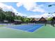 Community tennis court with green and blue surface, complete with lighting for evening play at 938 Crescent River Pass, Suwanee, GA 30024