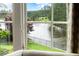 Window view of a calm lake, lush green grass, and mature trees on a sunny day at 938 Crescent River Pass, Suwanee, GA 30024