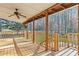 This covered wooden deck features a ceiling fan, a wood railing, and a view of a wooded backyard at 326 Bethel Dr, Woodstock, GA 30189