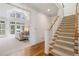 Bright foyer showcases a staircase with carpeted steps and access to a living room with large windows and hardwood flooring at 407 Spring House Ne Cv, Atlanta, GA 30307