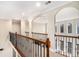 Spacious hallway featuring arched entryways, iron railings, and views to the outdoors through large windows at 6350 Old Wood Hollow Way, Buford, GA 30518