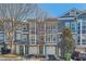 Charming townhomes boast large windows, attached garages, and vibrant turquoise doors, set against a backdrop of mature trees and blue skies at 1059 Park Row North Se, Atlanta, GA 30312