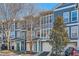 Charming townhomes boast large windows, attached garages, and vibrant turquoise doors, set against a backdrop of mature trees and blue skies at 1059 Park Row North Se, Atlanta, GA 30312