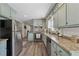 Well-lit kitchen featuring granite counters, stainless appliances, and sage green cabinetry at 4809 Thompson Mill Rd, Lithonia, GA 30058