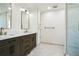 Bright bathroom featuring double sinks, stone countertops, dark wood cabinets, and a glass shower at 700 Hill Meadow Dr, Dacula, GA 30019