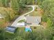Aerial view of home on wooded lot featuring a long driveway, pool, detached garage, and covered parking at 2517 N Hightower Trl, Conyers, GA 30012