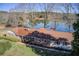 Aerial view of a charming house with a red roof and shutters, nestled by a serene lake and lush trees at 5010 Highway 20 Ne, Conyers, GA 30012